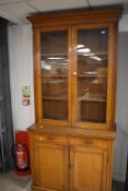 A late 19th Century golden oak bookcase, having dual drawers and cupboard to base, with brass