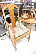 An early 20th Century oak carver chair having shaped back with scroll arm, drop in seat and part