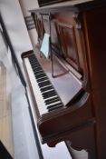 A late 19th or early 20th Century upright piano having overstrung action on metal frame, in mahogany