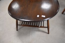 A dark stained Ercol coffee table of oval form with spindle undertier, approx. 99 x 83cm