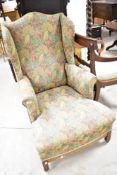 A late 19th or early 20th century wingback armchair having later floral upholstery