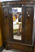 A late 19th or early 20th Century oak mirror door wardrobe having drawer base