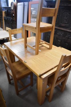 A modern golden oak extending dining table and four similar solid seat rail back dining chairs,