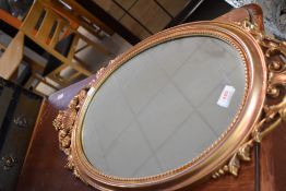 A reproduction gilt frame wall mirror having urn and swag decoration, approx. height 76cm