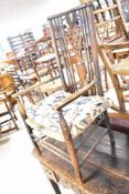 A late 19th or early 20th Century rush seater carver chair having spindle and wheelback