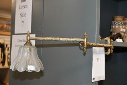A early 20th-century brass articulated library wall light, featuring an decorative Art Deco-style