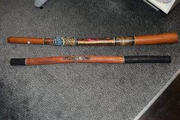 Two large vintage Aboriginal-style didgeridoos, the larger example having traditional dot-painting