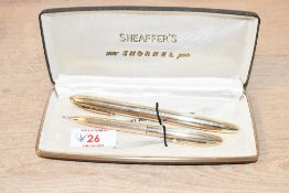 A boxed Sheaffer Touchdown Triumph Snorkel fill fountain pen and pencil set in parallel lined gold