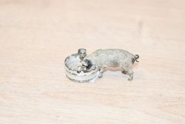 A sweet vintage brass pig with a painted finish, drinking from a pale, illegible mark to base,