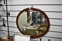 An early to mid 20th-century oval mahogany framed mirror, unmarked but with hanging fixtures to