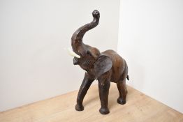 A mid 20th-century Liberty-style brown leather elephant figurine, featuring glass eyes and faux