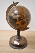 A mid 20th-century desktop wooden globe, featuring an 'Old World' 1492 map design, upon a turned