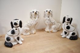 Two pairs of Staffordshire pottery spaniels, one with black painted and copper lustre