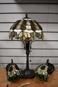 A 20th-century Tiffany-style table and two wall lights featuring green, cream and amber panelled