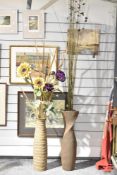 Two large floor standing faux flower arrangements in tall vases.