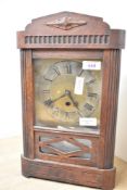 An early 20th-century wooden wall clock, featuring a decorative carved top and a glass-panelled
