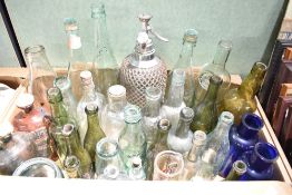 A selection of mixed antique and vintage glass bottles, including wire-bound soda siphon, coloured