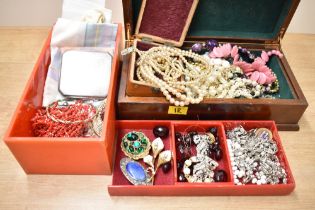 A wooden jewellery box along with a red plastic jewellery box, both containing an assortment of