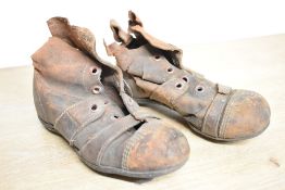 A small pair of early 20th-century brown leather child's football boots, featuring high ankles,