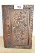 A vintage carved wood cigarette dispenser box, in the shape of a book, featuring floral detailing,