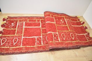 A small vintage Turkish-style runner rug, featuring red and gilt stitching of traditional motifs,