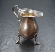A George V silver cream jug, of bulbous form having a generous spout opposed by a scroll handle,