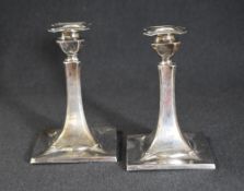 A pair of Edwardian silver candlesticks, having quatrefoil sconces, over square stems and square