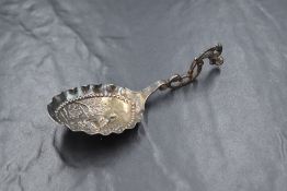 A Victorian Dutch import silver 'monkey spoon' having a decorative scroll handle and embossed bowl