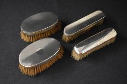 A George V silver mounted three piece vanity set, comprising three clothes brushes, having engine