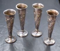 A group of four Victorian and Edwardian silver vases, of fluted form having embossed floral and