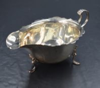 A George V silver sauce boat, having a Chippendale style rim with a narrow spout opposed by a scroll