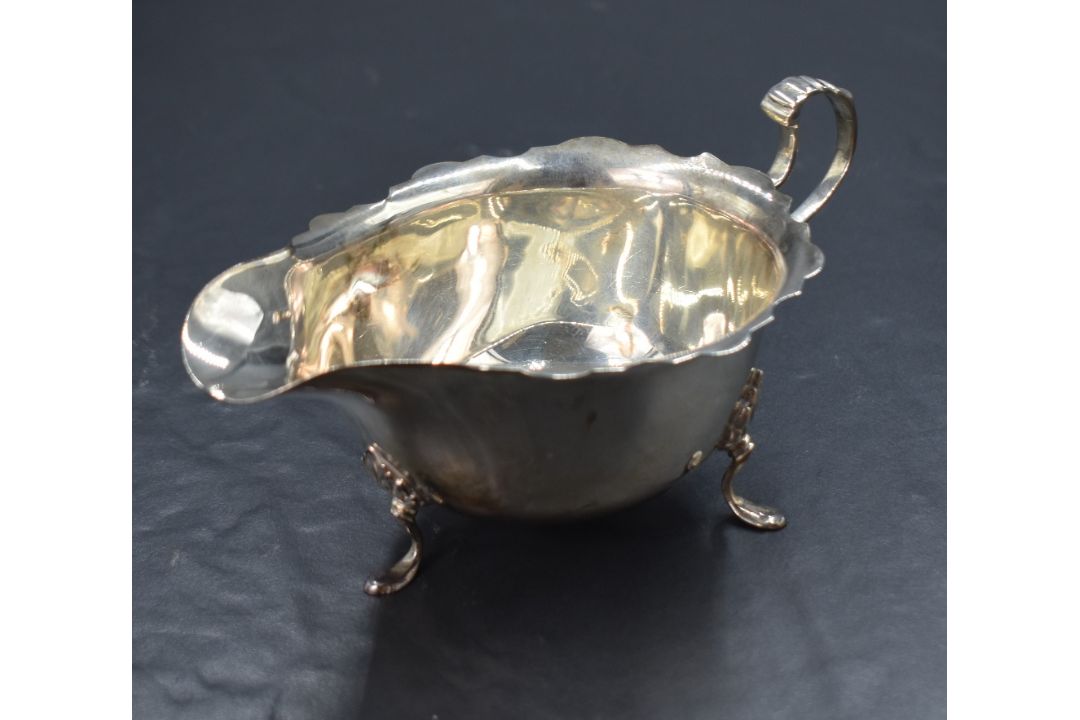 A George V silver sauce boat, having a Chippendale style rim with a narrow spout opposed by a scroll - Image 1 of 2
