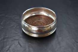 An Elizabeth II silver wine coaster, having a moulded rim with a wooden base, marks for London 1990,
