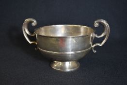 A George V silver pedestal bowl, having a moulded rim with ornate scroll handles to each side,