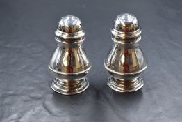 A cased pair of Victorian silver pepperettes, of bulbous form with moulding to the body, raised on