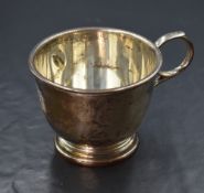 A George V silver cup, having a moulded rim with high loop scroll handle and monogram to the body