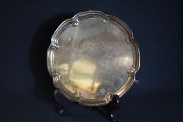 A George VI silver salver, of traditional form having a moulded lobed rim, raised on three scroll