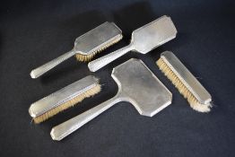 A cased silver mounted vanity set, comprising a hand mirror, two hair brushes, a comb and two