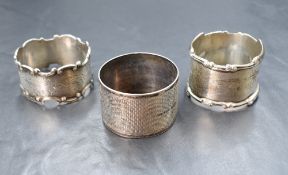 A group of three napkin rings, having engine turned decoration, foliate engraving and scroll