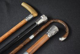 A group of four silver and white metal mounted walking canes, one having a curved handle, one having