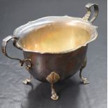 A George V silver sugar bowl, having a Chippendale style rim with scroll handles, raised on four