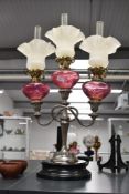 An early 20th century French brass, cranberry glass and silver plated three branch oil lamp, the