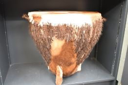 A large late 20th-century African drum-formed side table, covered in brown and white cowhide, upon