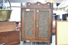A Victorian/Edwardian carved oak smokers cabinet, featuring rose motifs having two internal drawers,