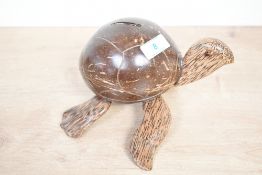 A vintage coconut shell turtle-shaped moneybox, featuring a polished shell body with sweetly