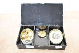 A money-box tin containing a small assortment of cufflinks, collar studs and brooches