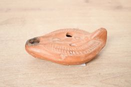A small late Roman-style red ware pottery oil lamp, of elongated form having a faint central figural
