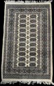 A 20th century wool Bokhara rug having a beige ground, black and honey accents, having a central
