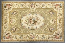 A 20th century room-sized rug made in cross-stitched wool using khaki, warm neutrals, poder blue and