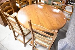 An Ercol circular (extending) dining table and six similar ladder back chairs in mid stain